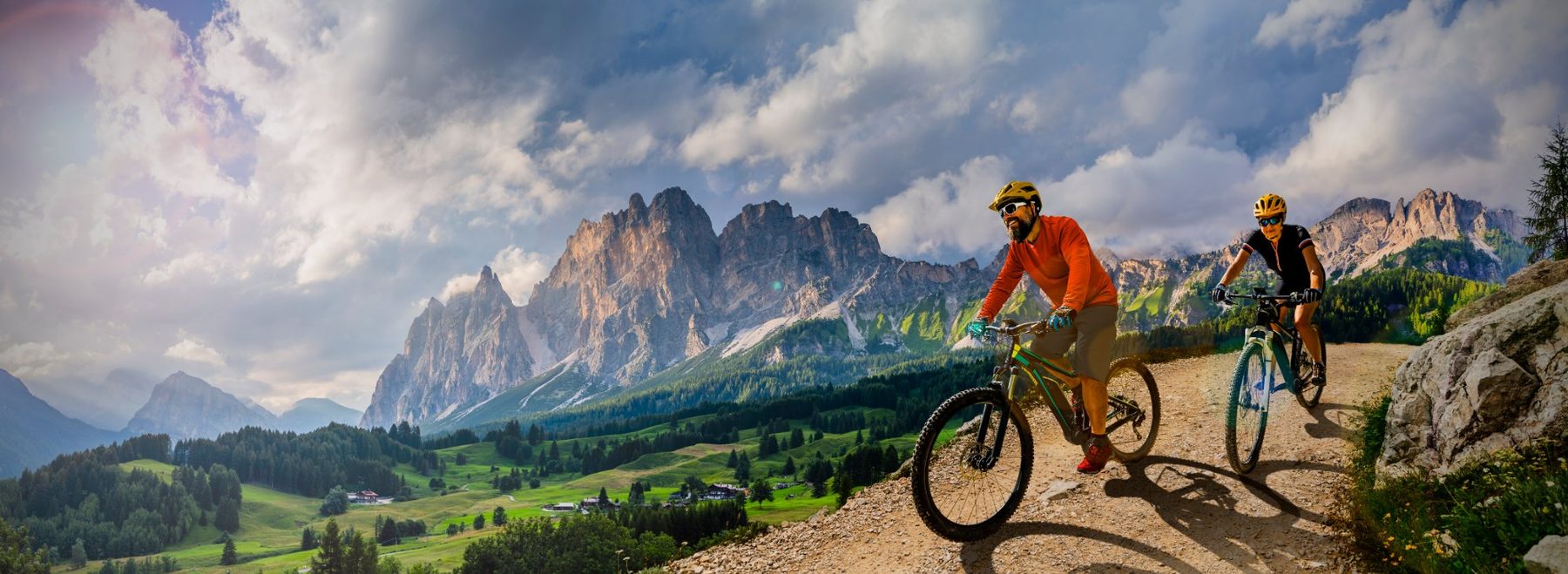 Two mountain bikers pausing on a dramatic mountain trail.